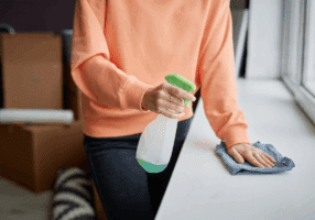 Person cleaning a smooth surface with spray and cloth in a home ensuring a tidy living area.